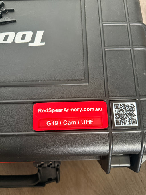 Black toolbox with a red label and QR code on a wooden surface