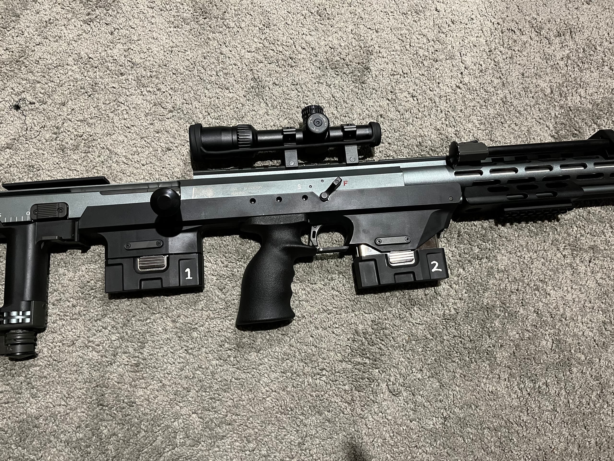 Black rifle with attachments on a gray surface