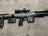Black rifle with attachments on a gray surface